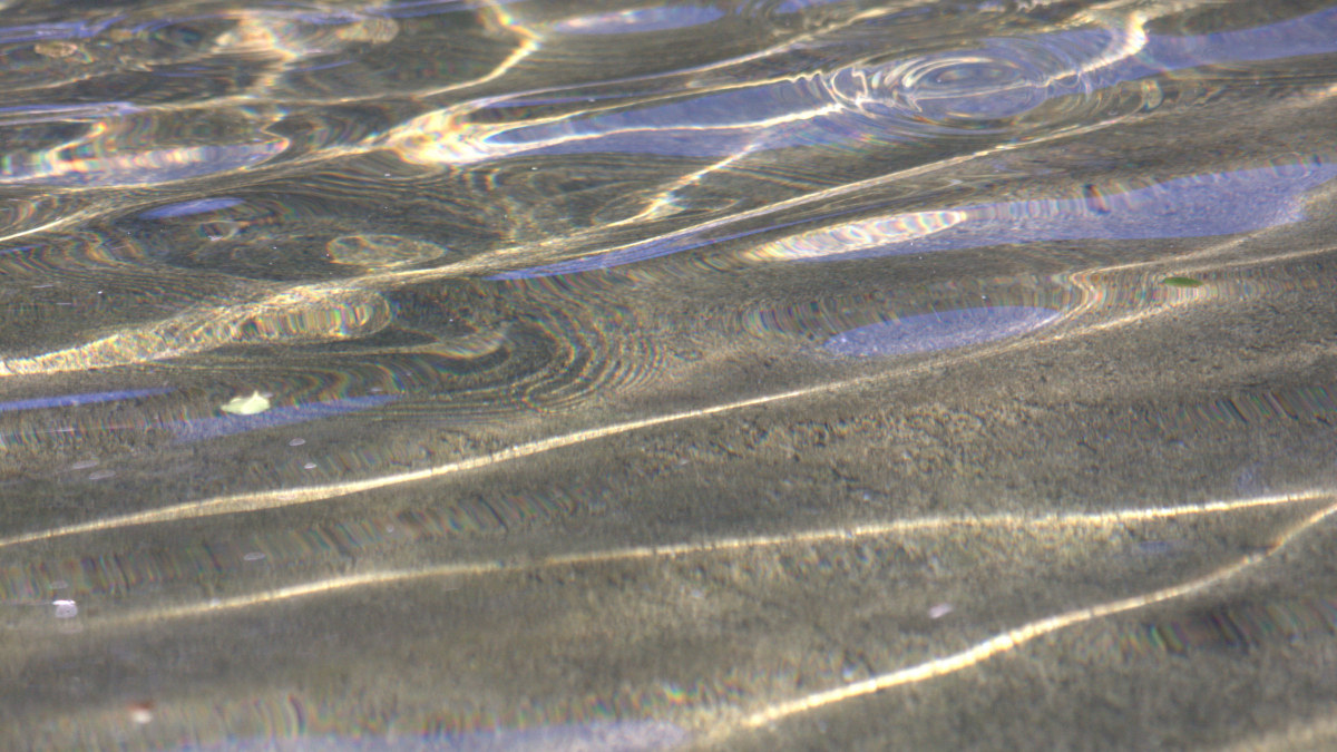 Sunlight makes rainbows in quietly rippling water.